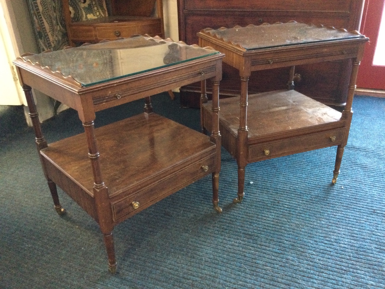 A pair of mahogany tables with plate glass tops framed by raised scalloped galleries above slides,