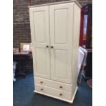 A modern painted pine wardrobe with fielded panelled doors enclosing hanging space above two long