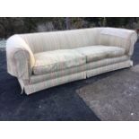 A large country house sofa, with wide padded back & arms having loose cushions, raised on turned
