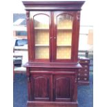 A Victorian style mahogany bookcase with moulded cornice above arched glazed doors enclosing a