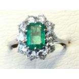 A white gold emerald and diamond ring, the baguette cut stone approaching .75 carats framed by ten