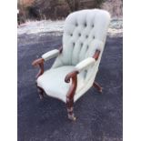 A Victorian mahogany armchair with button upholstered back and scroll carved arms with elbow pads,