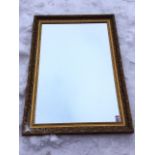 A large gilt framed mirror, the frame with embossed scrolled decoration, having inner leaf moulded