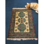 A Turkish wool rug woven with three green aztec style panels with hooked motifs on cream field,
