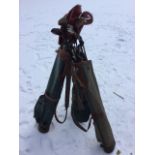 Three vintage golf bags, some with leather mounts, containing a quantity of golf clubs - some with