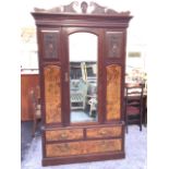 A Victorian walnut wardrobe with scroll carved shell pediment above a moulded cornice, the arched