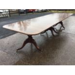 A Georgian style three pedestal mahogany dining table, the crossbanded rounded top with reeded