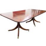 A Georgian style twin pedestal mahogany dining table, the top with spare leaf having ribbed edge,