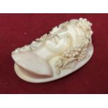 A nineteenth century carved ivory brooch depicting Bacchus, the finely detailed bust with vines to