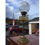 A Victorian brass oil lamp with acid etched globe shade above a twin-wick and ribbed glass