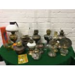 A collection of Victorian brass oil lamps, many with chimneys, together with a book - Discovering