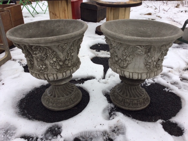 A pair of composition stone garden urns moulded with horned masques and fruit swagged garlands,