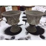 A pair of composition stone garden urns moulded with horned masques and fruit swagged garlands,