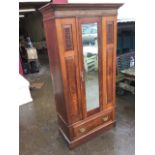 A Victorian walnut wardrobe with moulded cornice above a central bevelled mirror door flanked by
