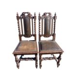 A pair of carved Victorian oak hall chairs with leaf decoration to back rails, flanked by