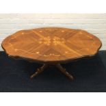 An inlaid oval scallop top walnut coffee table with waved apron on quadripartite pedestal. (46.5in x