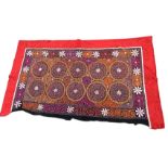A Mongolian wall hanging embroidered in coloured wools with panel of circular medallions with