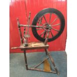 An antique mahogany spinning wheel with treadle mechanism on three angled turned legs, having