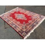 A Belgian oriental style rug woven with red field having floral medallion and spandrels, the
