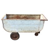 A galvanised truck on wheels, having flat rim and barrow handle to one end. (59in x 29in x 34in)