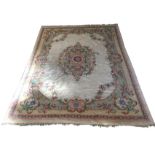 A wool carpet with central oval floral medallion on cream ground with conforming pastel floral