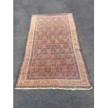 An oriental rug woven with busy field of diamond shaped medallions on charcoal ground, the frieze of
