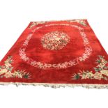 A Chinese thick pile carpet woven with oval floral medallion framed by border of leaves on orange
