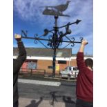 A large weather vane surmounted by a fretwork pheasant above a swivelling arrow and compass points