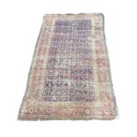 An antique oriental rug woven with busy floral field on blue ground, framed by border of linked