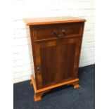 A reproduction yew crossbanded cabinet, the moulded top above a frieze drawer and cupboard, raised