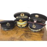 Five military caps with shaped peaks, buttoned chinstraps, and all badged - Russian, American,