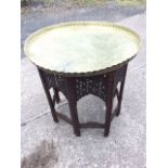 An eastern brass tray top table, with scalloped rim framing top engraved with seven circular