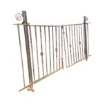 A pair of garden gates with twisted vertical bars on square gateposts, having scrolled mounts. (