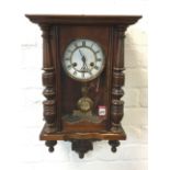 A late Victorian walnut cased Vienna wallclock, with moulded cornice above an arched door flanked by