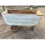 A galvanised truck on wheels, the shaped riveted trough with flat rim having handle to end. (59in