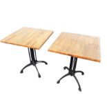 A pair of square tables with hardwood tops on column supports, with arched legs on hoof feet. (