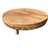 An African drum coffee table, the stretched skin top sewn with twisted thongs above a skin covered
