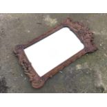 A carved walnut mirror, with scroll carved decoration having leaf pillars to sides and flowerheads