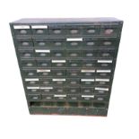 A metal cabinet containing 48 small drawers mounted with cup handles, with open compartment