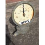 A diesel gallon meter with circular dial and counter under glass with chromed frame, having pipework