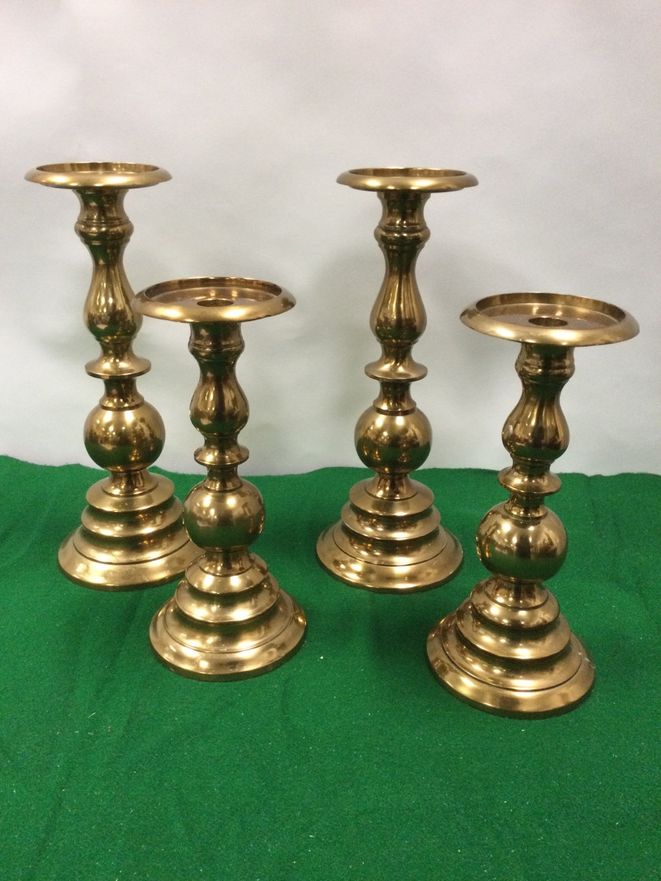 A pair of metallic copper candlestands with turned columns on circular moulded bases; and another