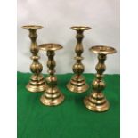 A pair of metallic copper candlestands with turned columns on circular moulded bases; and another