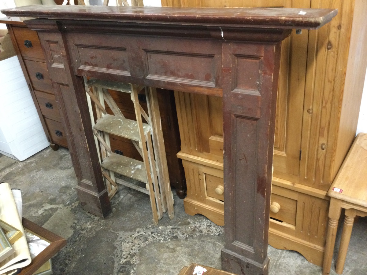 A stained chimneypiece with moulded mantelpiece above a panelled frame, the jambs on moulded plinth.