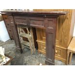 A stained chimneypiece with moulded mantelpiece above a panelled frame, the jambs on moulded plinth.