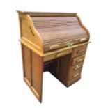 An oak roll-top desk, the tambour enclosing a fitted interior with small drawers and pigeonholes,