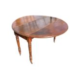 A circular late Victorian mahogany dining table, the moulded top with drop leaves raised on turned