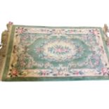 A Chinese thick-pile rug woven with pastel flowers on pale green ground, having tassels to ends. (