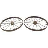 A pair of agricultural wheels having concave rims framing spokes around cogged hubs. (46in dia) (2)