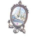 A brass dressing table mirror, the oval frame with bevelled plate surmounted with crest of flowers