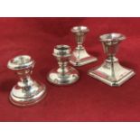 A pair of hallmarked silver candlesticks with square moulded bases supporting urn shaped